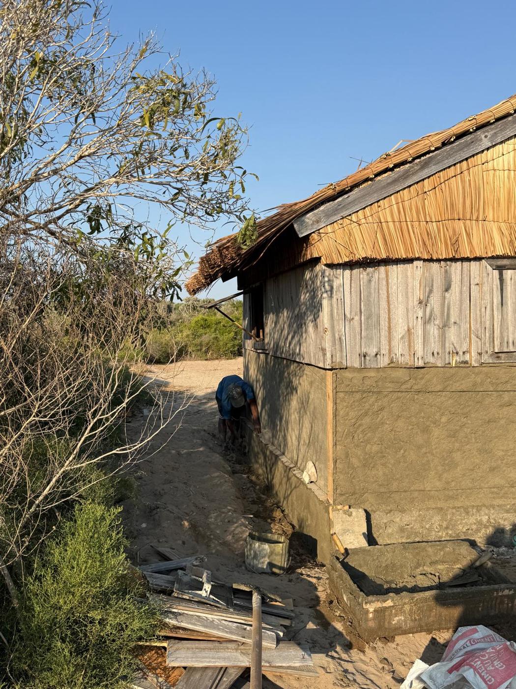 Un artisan pose l'enduit sur le soubassement d'un logement
