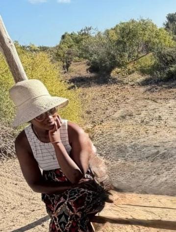 Papousy, assise à l'ombre, coiffée d'un chapeau